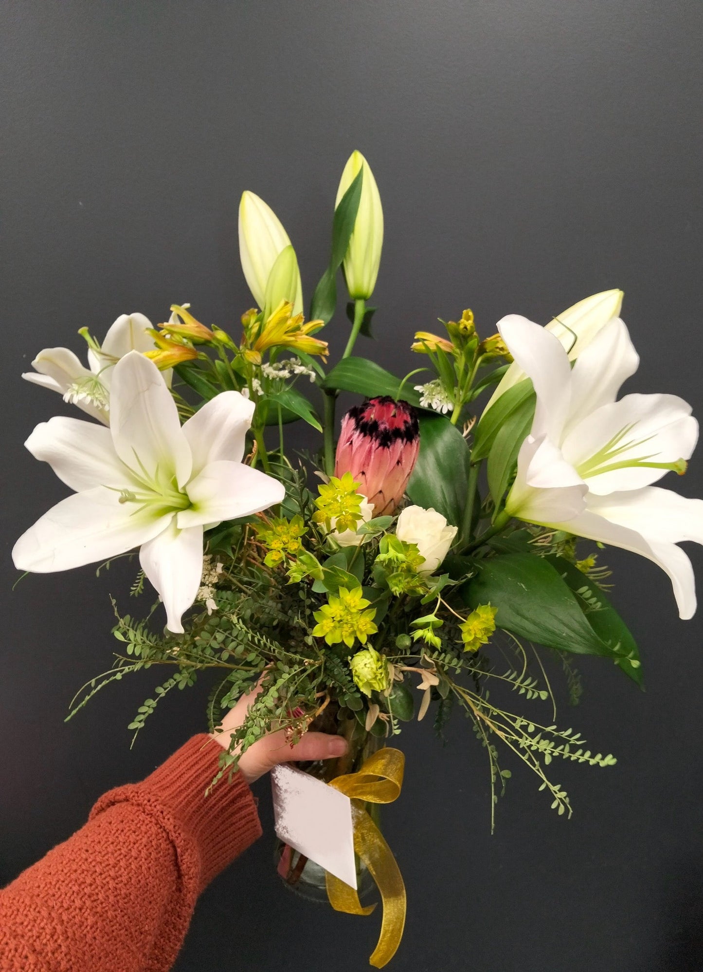 Bouquet of flowers held by a person against a dark background