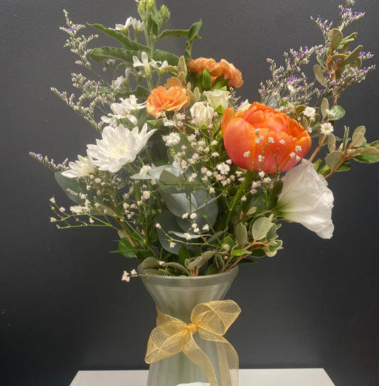 Bouquet of flowers in a green vase with a yellow ribbon