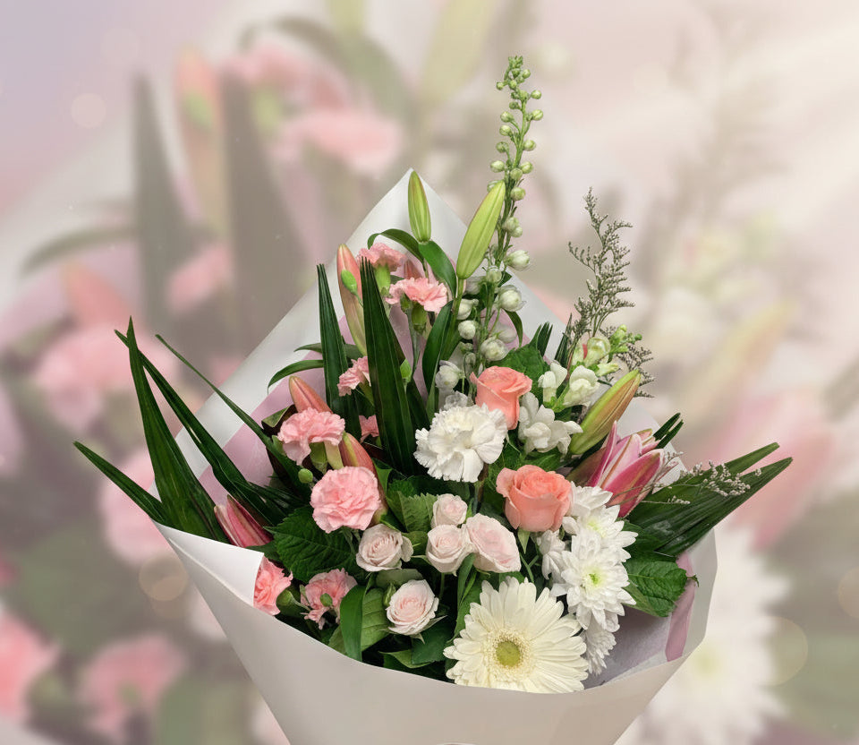 Elegant bouquet of mixed pink roses, lilies, carnations, white daisies, and greenery wrapped in white paper