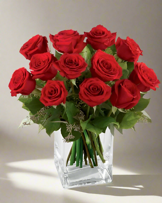 Bouquet of red roses in a clear vase on a neutral background