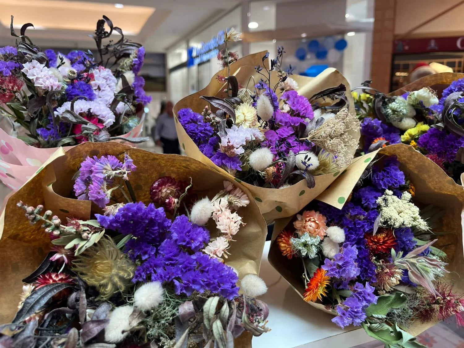 Bouquets of dried flowers with vibrant purple, white, and orange hues wrapped
